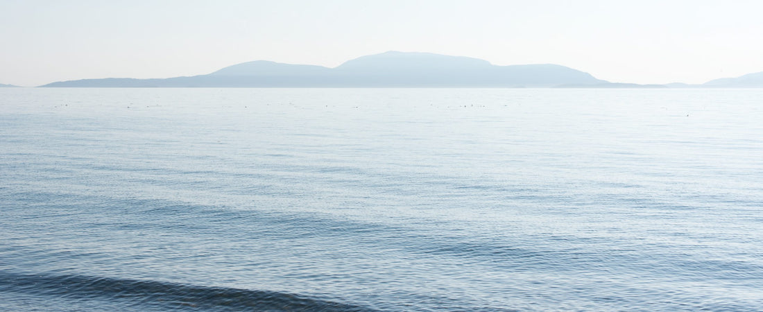 A blue ocean scene of distant islands in the background and waves in the foreground.