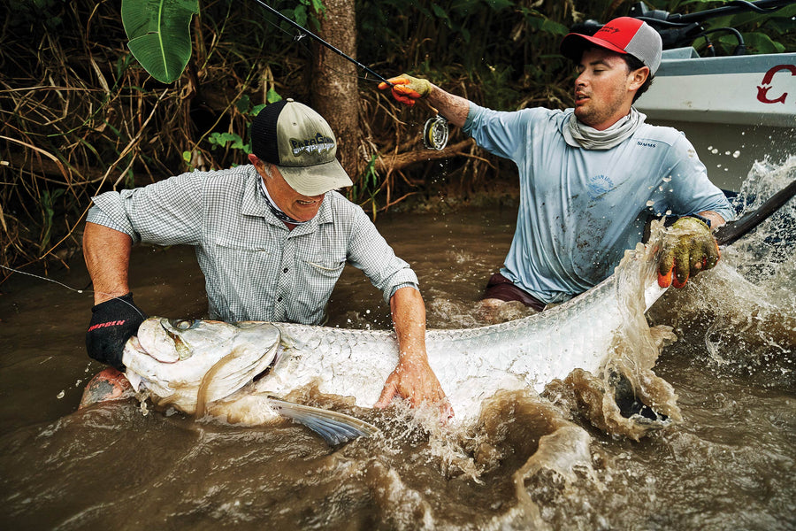 Guest of Tapam Lodge Greg Bostater and guide Isaac Sebastian wrestling and unhooking a tarpon in the shallows. Photo: Max Bartholin