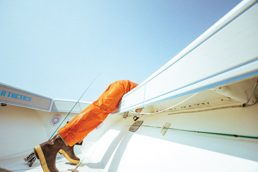 Half of Blane Chocklett, less-than-firmly planted inside of a boat, while the other half releases a Cape Cod striper.